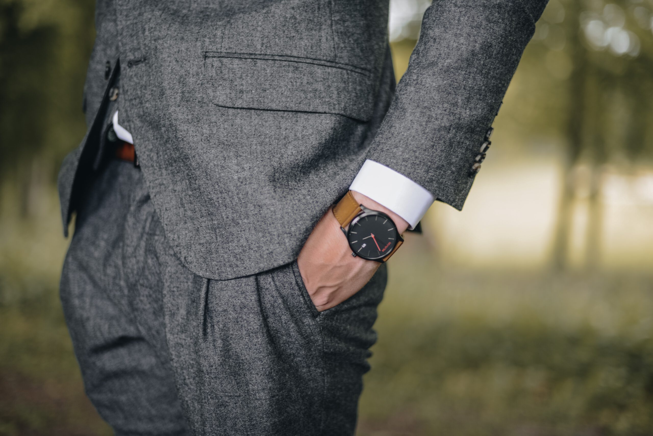 Mężczyzna w garniturze trzymający rękę zegarkiem w kieszeni